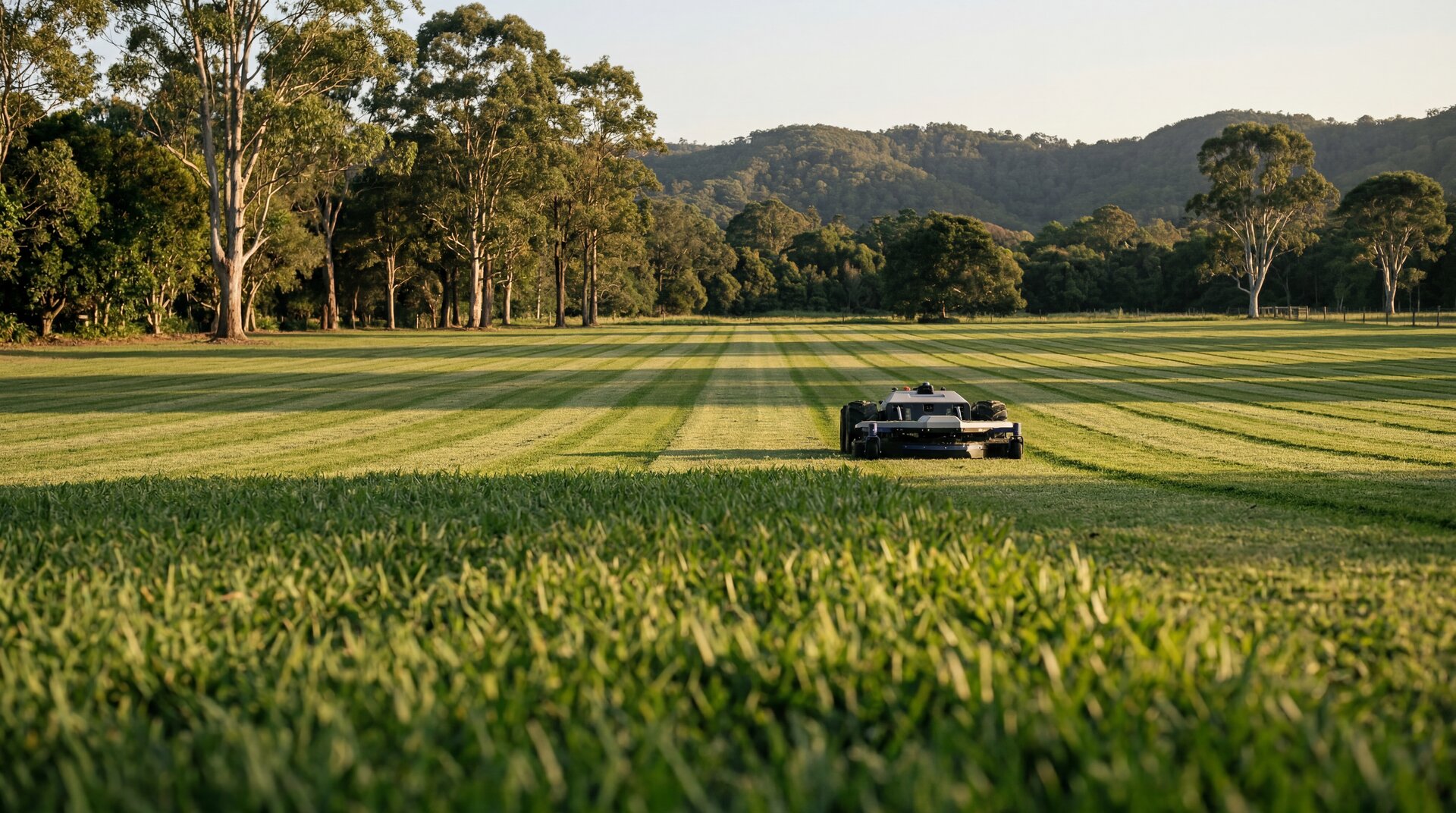 Autonomous mower laying clean stripes across a Northern Rivers paddock — the operational reality the FAQ answers questions about